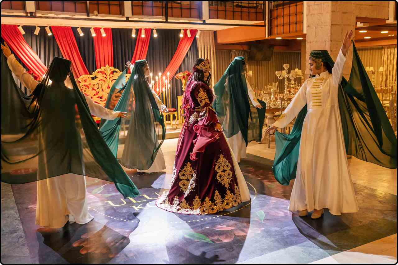 Group of women, including the future bride, dancing in traditional attire at Kina Gecesi, with festive decorations in the background.